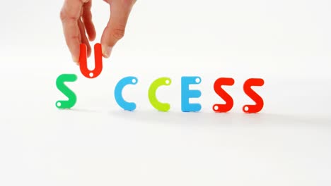 hand putting the word success with alphabet