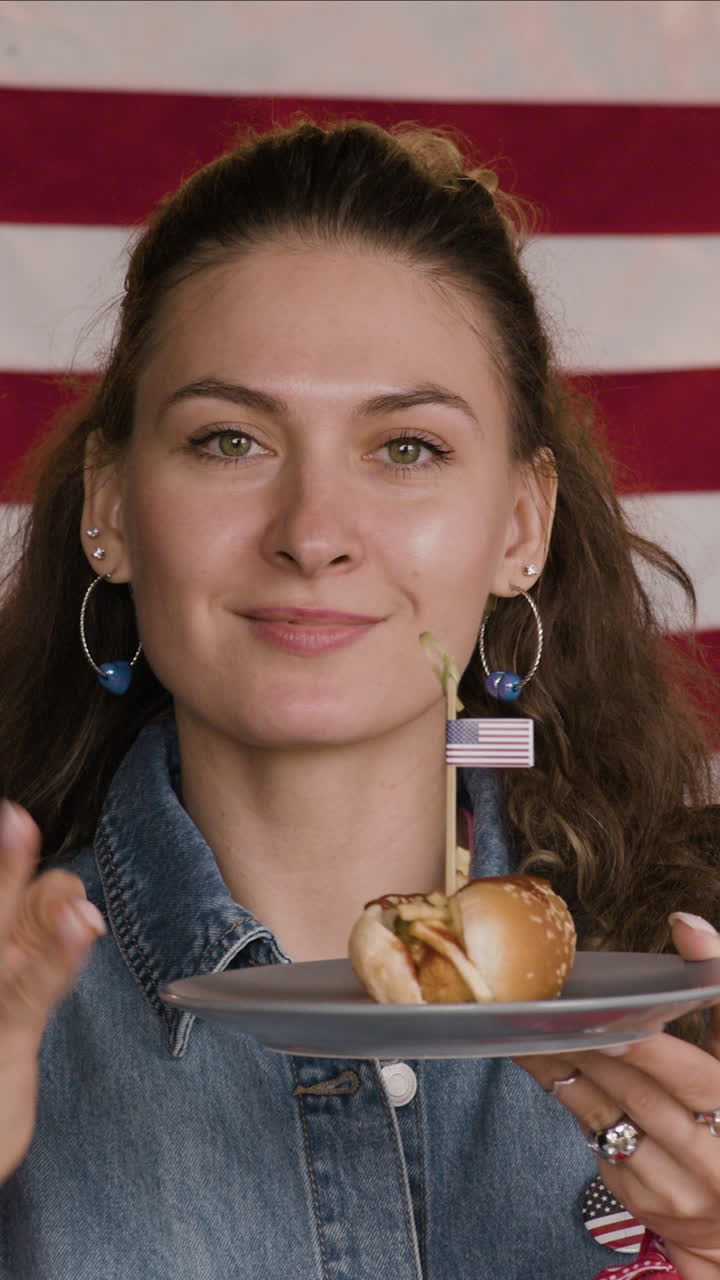 Woman eating a hot dog with an American flag toothpick
