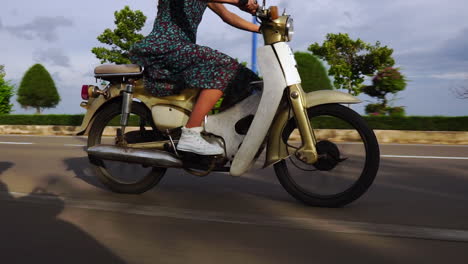 mujer montando motocicleta a lo largo de la carretera en cámara lenta con vestido de verano