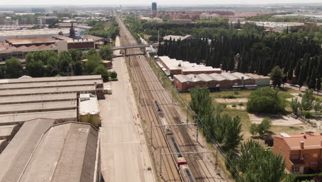 passenger train driving through suburbs of madrid, aerial drone view