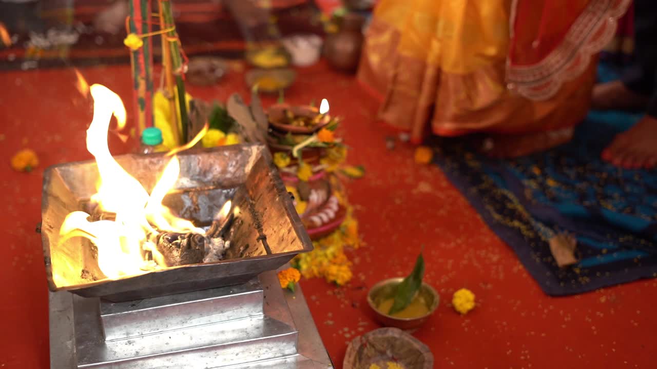 Close up shot of a fire (yagna) with Hindu couple in background during traditional Hindu wedding in India. Slow motion shot