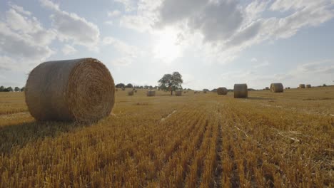 Weitwinkel-Zeitraffer-Des-Lichts,-Das-Sich-über-Ackerland-Rund-Um-Heuballen-Am-Hang-Ausbreitet