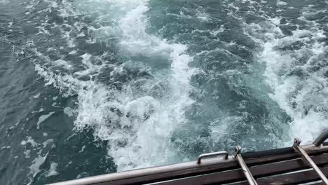 foam, waves and bubbles forming in the wake, back of a sailing boat