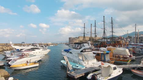 view from kyrenia's old harbour crowded with boats with a backdrop to the ancient castle - wide slide reveal shot