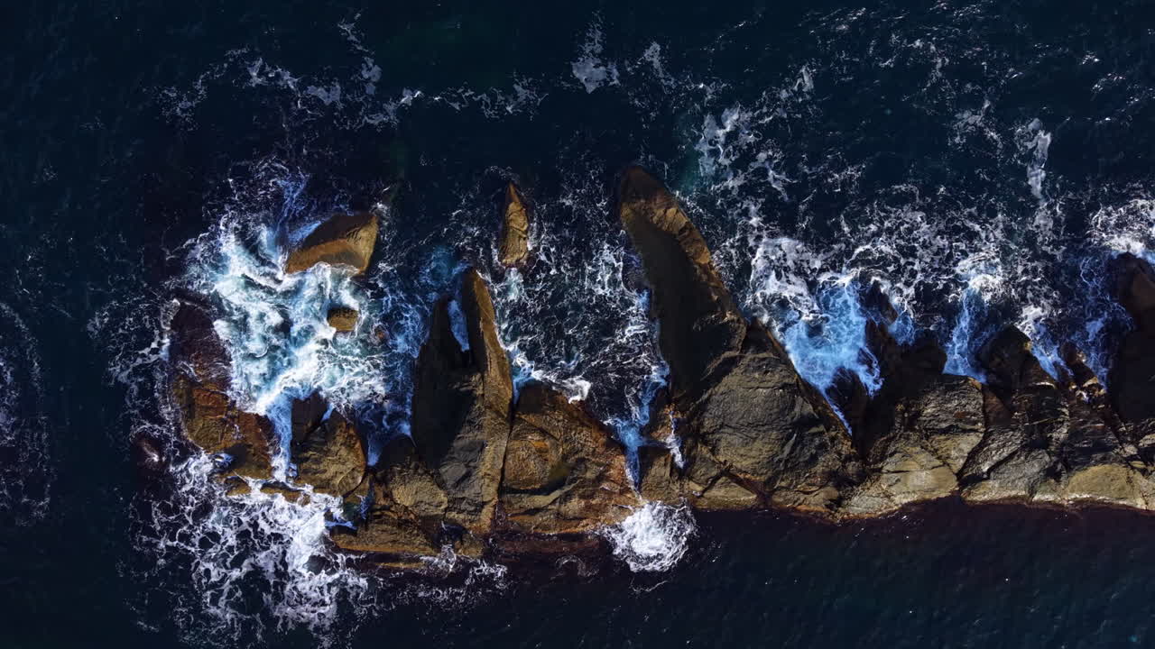 Waves crashing against rocky shores at dawn reveal nature's raw power and beauty near a secluded coastal paradise