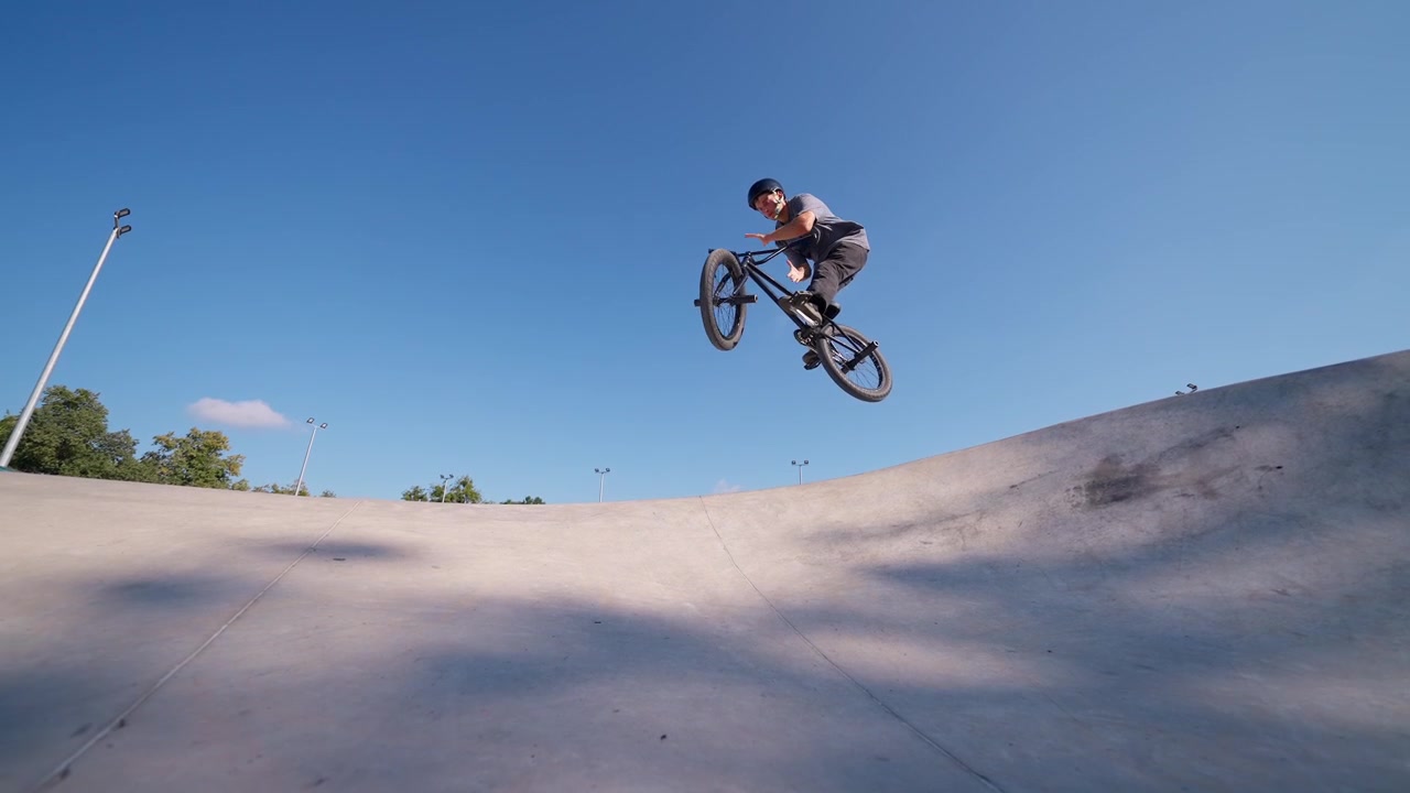 Giovane uomo che esegue un salto in BMX in uno skatepark di cemento