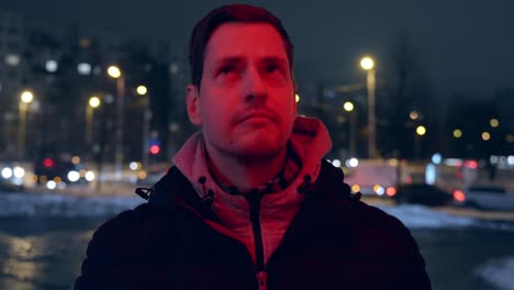 close-up of a man with a worried face waiting for a red traffic light while the light shines in his face