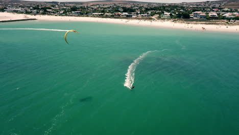 Scenic-high-altitude-drone-pickup-wide-shot-of-kite-surfing-on-Langebaan-beach,-South-Africa-with-perfect-sunny-holiday-weather