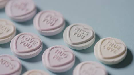 full frame shot of heart candy with romantic messages of love on blue background