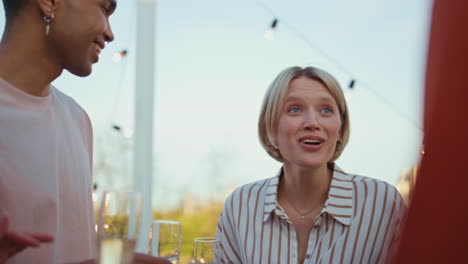 emotional woman telling story rooftop event close up. friends drinking champagne