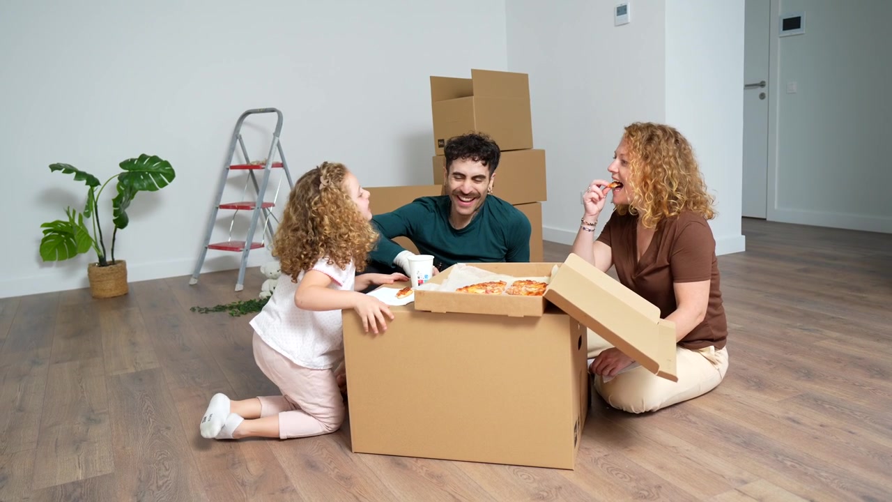 Young Family Eating Pizza on the Floor in Their New Home