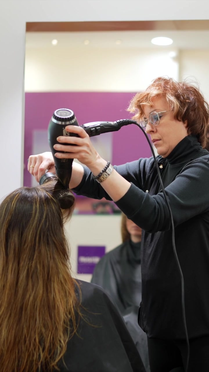 Professional Hairdresser Blow Drying Client's Hair in Salon