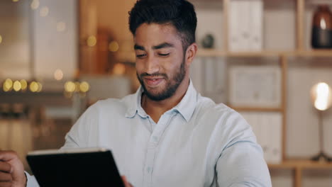 Business-man-laughing-on-tablet-in-dark-office