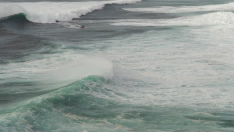 surfeando olas grandes en nazare, portugal, surfista y conductor de motos acuáticas, deporte extremo, vista panorámica