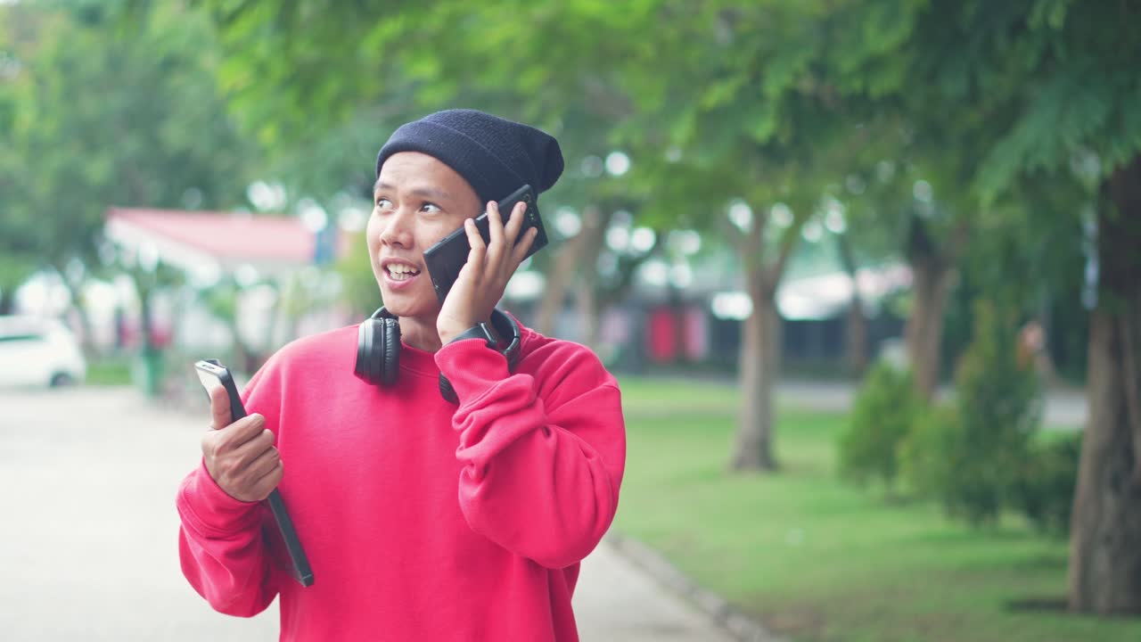 hombre asiático ocupado freelance recibiendo llamadas telefónicas y hablando hace una cita mientras camina en el parque