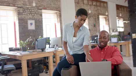 Happy-african-american-colleagues-using-laptop-and-talking-in-creative-office,-slow-motion