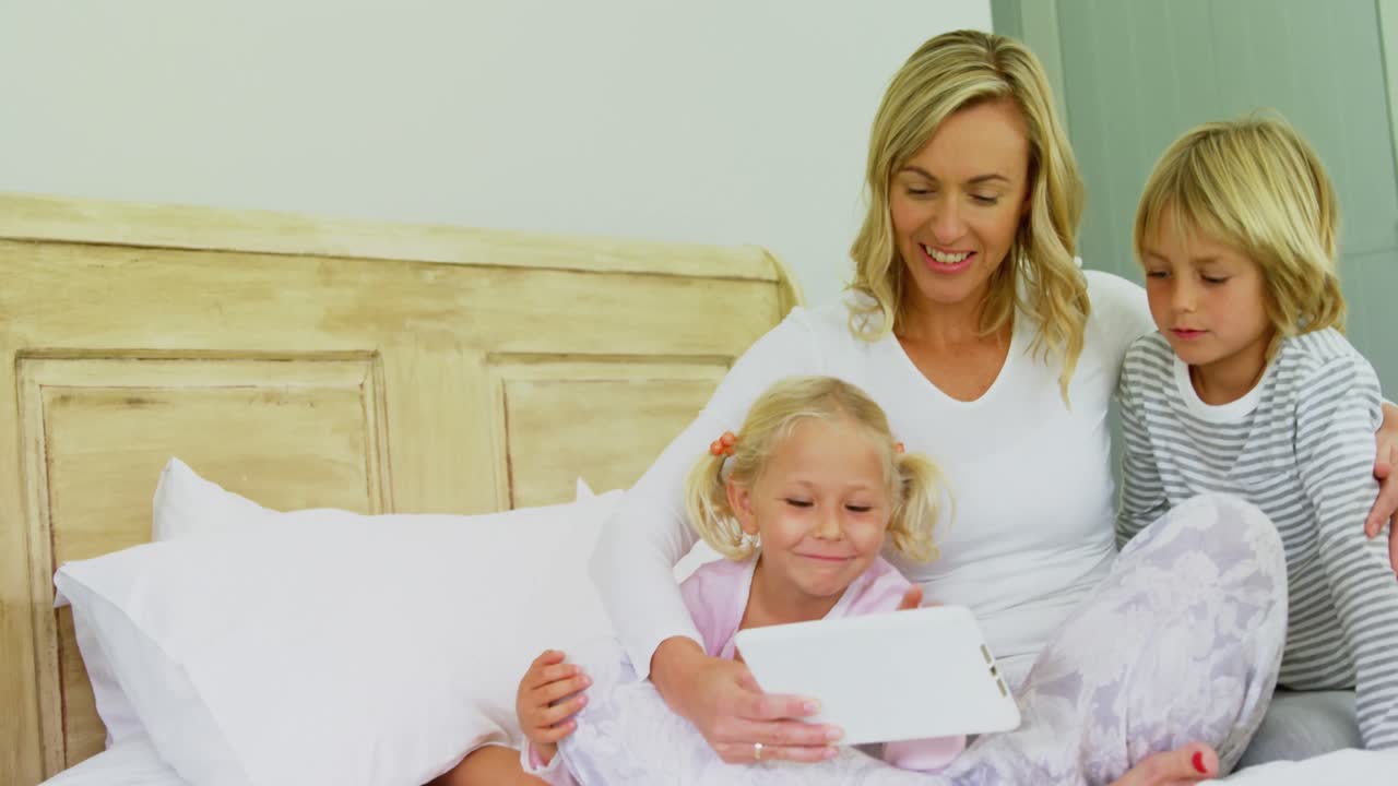 Kinderen en moeder gebruiken digitale tablet in slaapkamer 4k