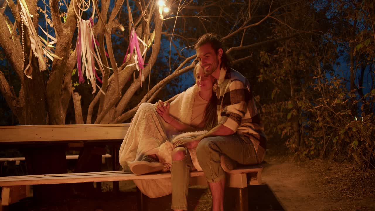 A couple in love are hugging and looking at the bonfire. Party outside the city. Rest in the country house