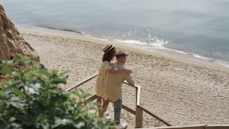 romantic pair hugging standing beach staircase enjoying summer ocean view.