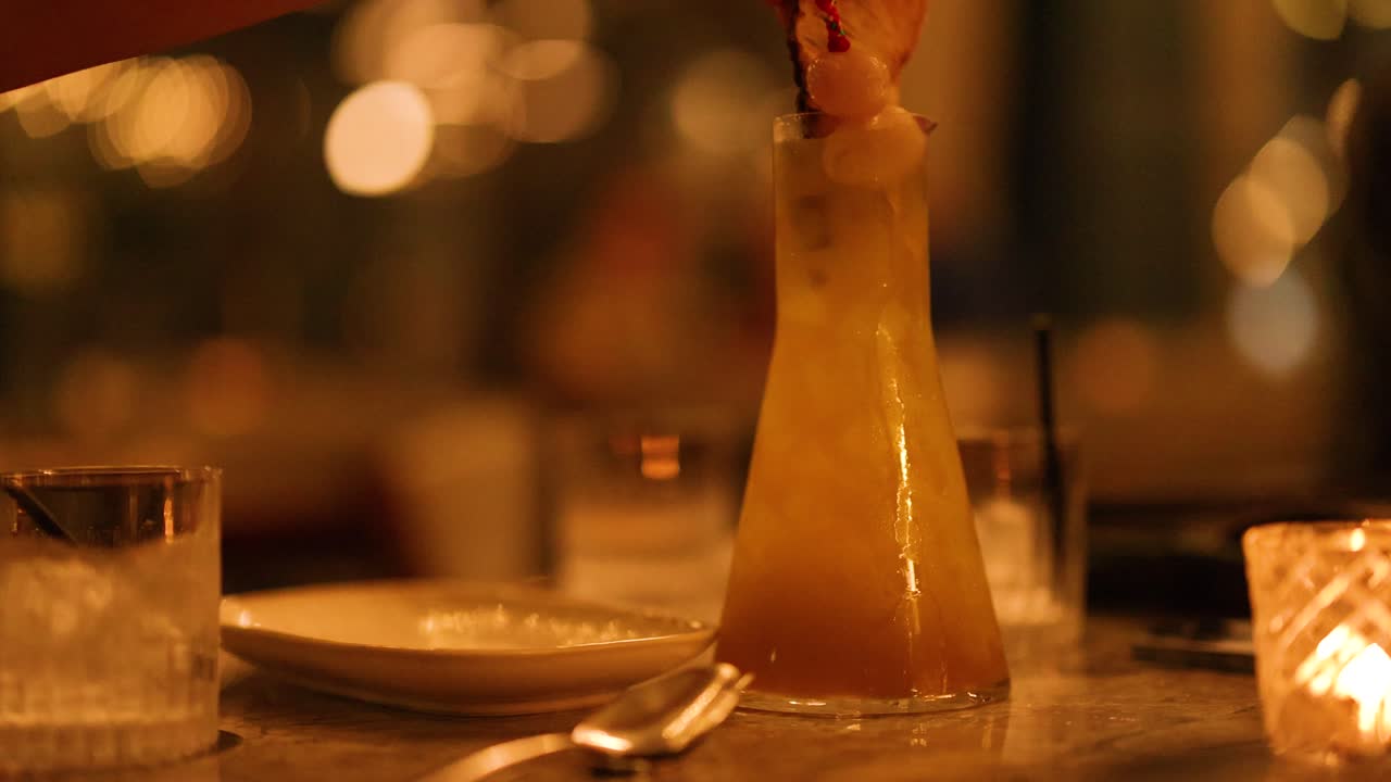 A vibrant cocktail is elegantly served on a dimly lit table, creating a warm and inviting atmosphere
