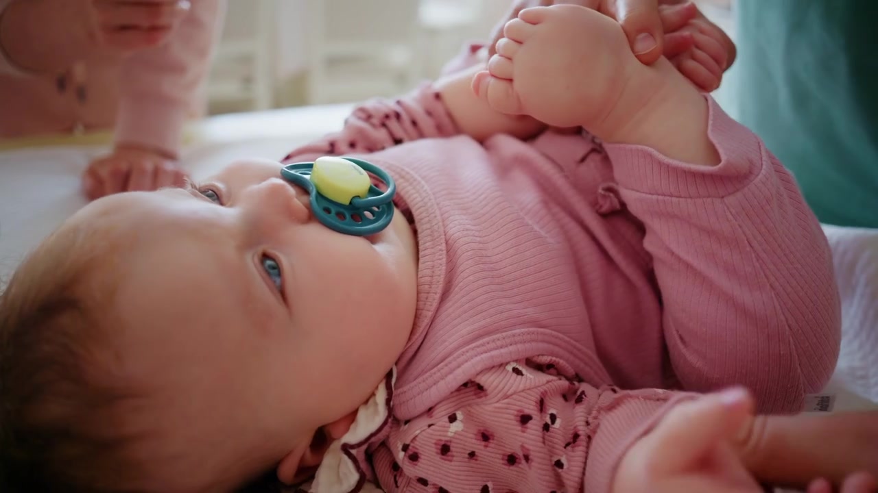 Baby lying on a treatment table with a pacifier while adults provide gentle support during a pediatric therapy session