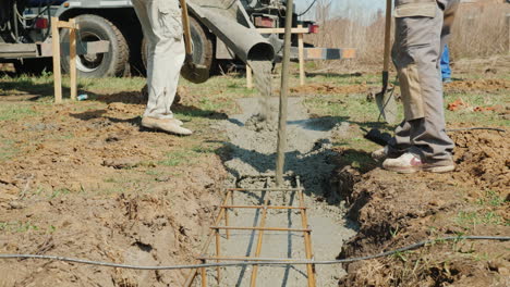 a worker with a vibrator and shovel takes concrete from the mixer heavy manual labor at the construc