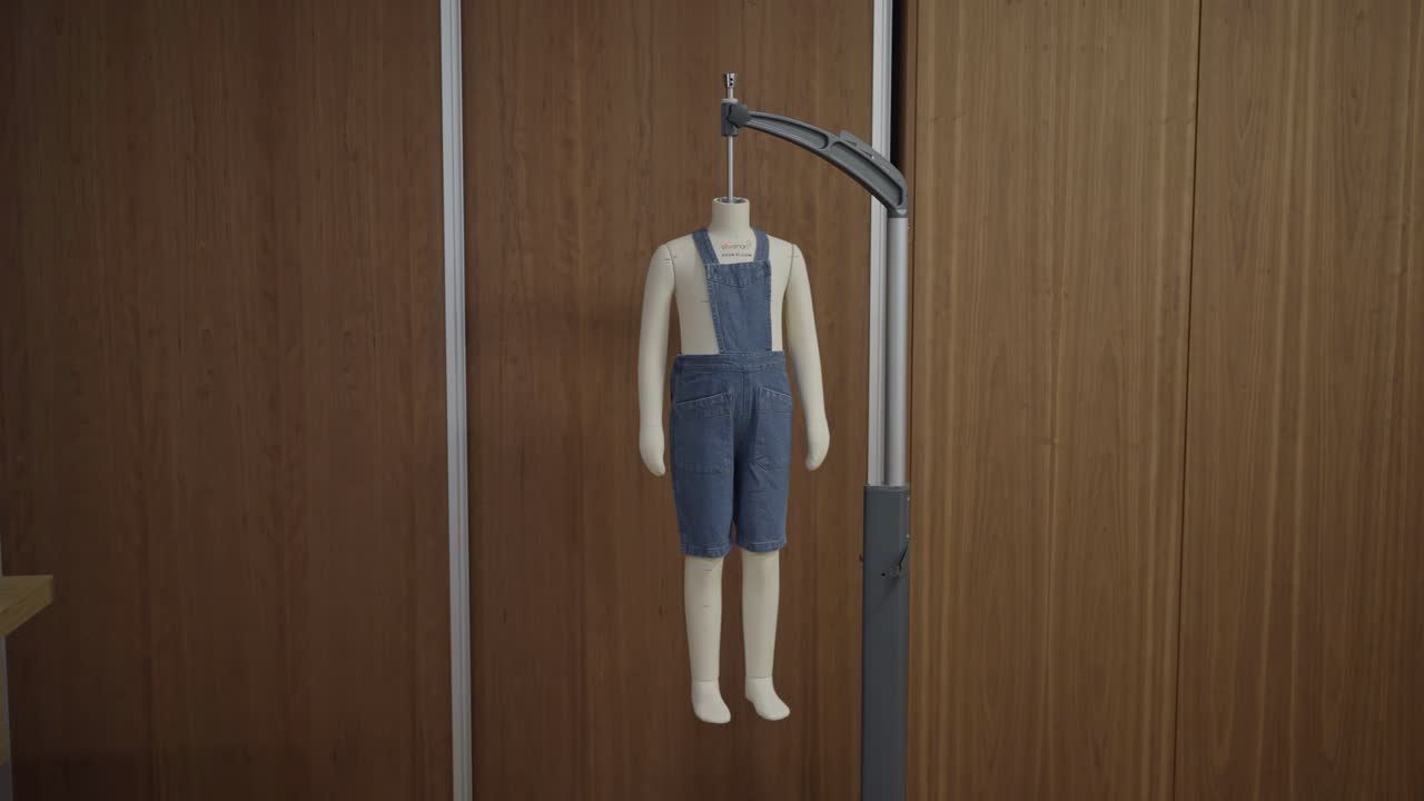 Manichino bambino vestito con una tuta di jeans esposto in un interno di uno studio