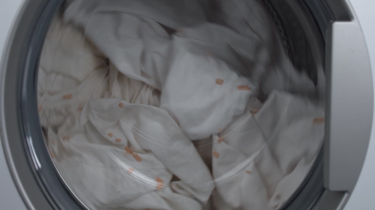 세탁기 중간 로드 사이클에서 회전하는 더러운 옷과 리넨