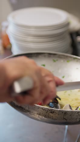 chef plating a gourmet dish of spaghetti with mussels