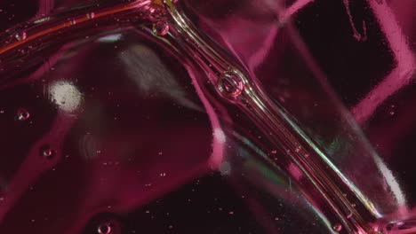 macro shot of tiny soap bubbles sliding between bigger bubbles against dark red background