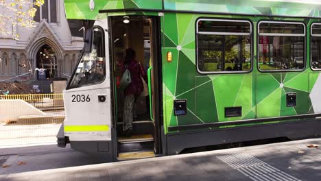 individuals boarding a green tram in melbourne