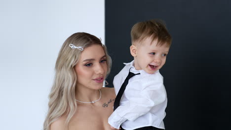 attractive blonde woman is holding a lovely baby boy. portrait of a mother and child in studio.