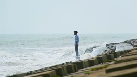 beauty and danger of nature as man watches the waves crash in on him