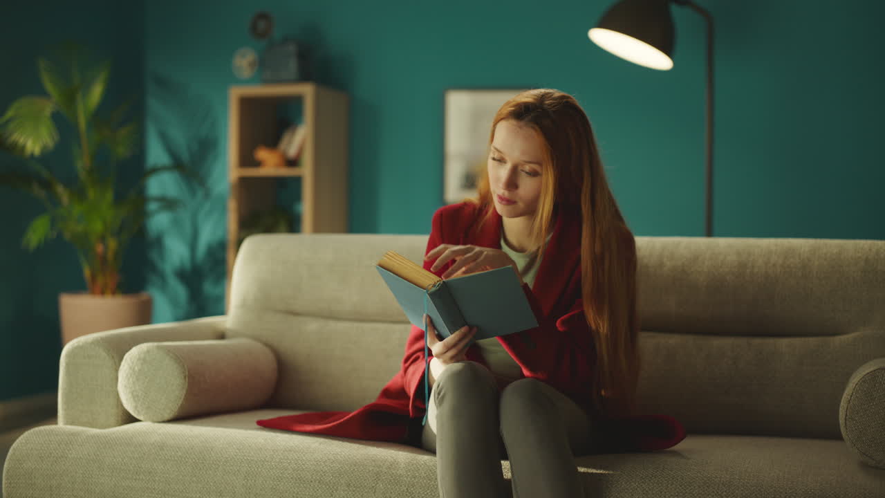 Woman reading a book sitting on sofa