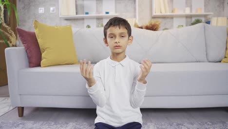 muslim boy praying at home with open hands.