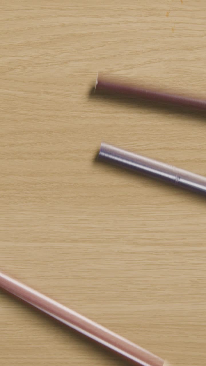 다채로운 연필이 나무 바탕으로 굴러가는 수직 비디오