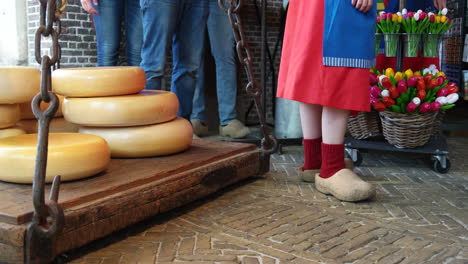 dutch people at the de goudse waag museum and market in gouda, netherlands with gouda cheeses and tulips in display