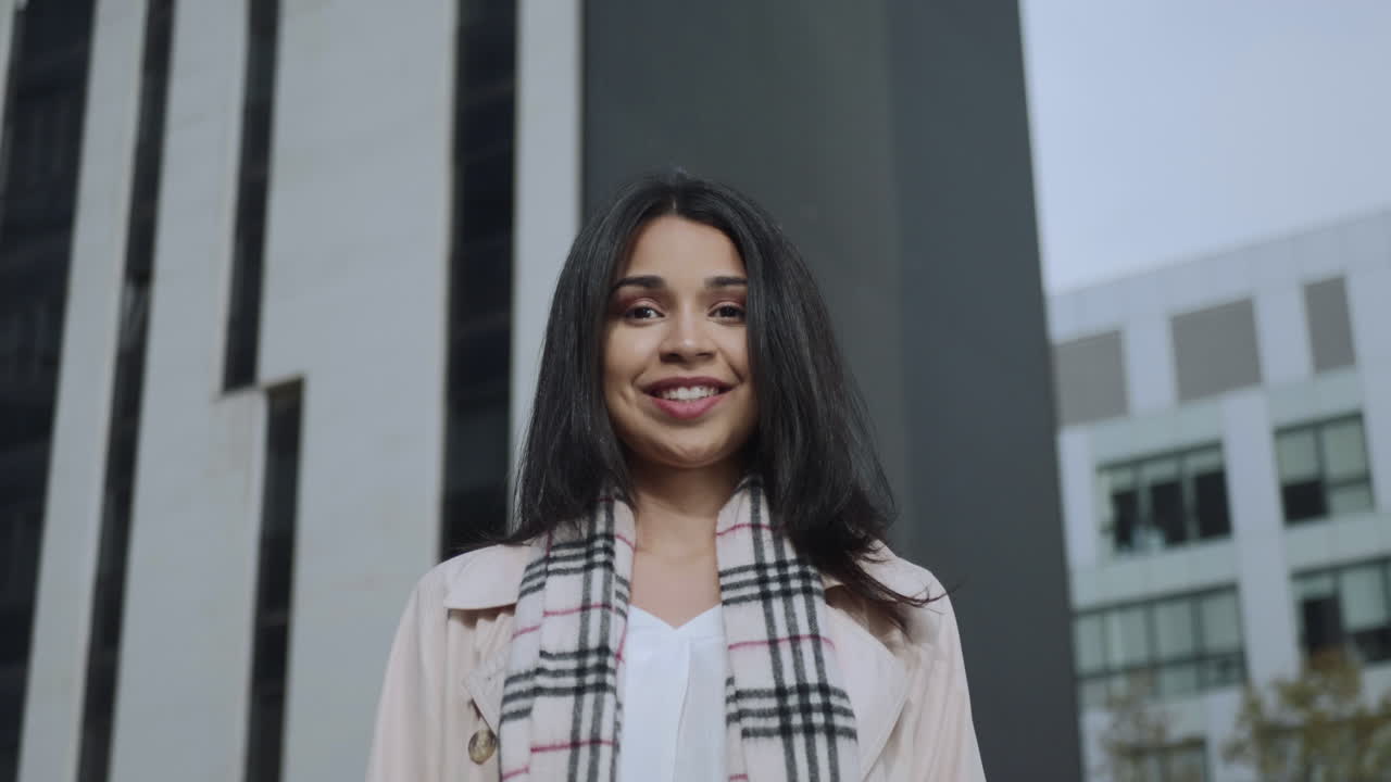 Glad forretningskvinde kigger ind i kameraet på gaden. Forretningsdame smiler udendørs.
