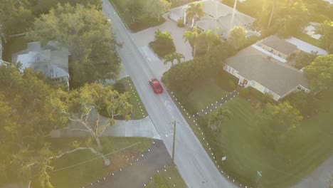 一架红色跑车在日落时穿过南佛罗里达街的空中景象