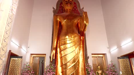 un video sereno que muestra la majestuosa estatua dorada de buda en wat pho, bangkok, con detalles intrincados del templo y iluminación suave