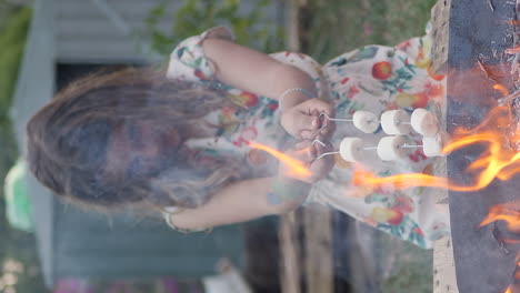 young girl roasting marshmallows on metal sticks over fire