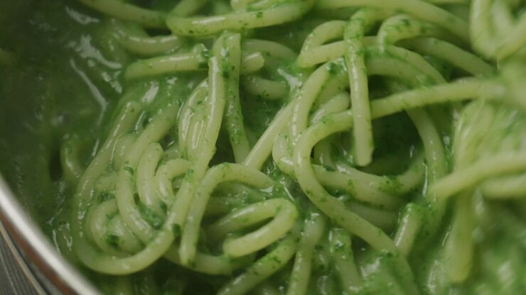 Stirring Pasta with Green Spinach Sauce during Cooking