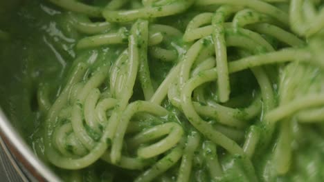stirring pasta with green spinach sauce during cooking