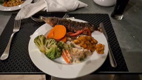 Delicious-fresh-fish-with-vegetables-served-in-white-plate,-close-up