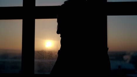 silhouette-of-woman-at-large-window-in-dark-flat-close-view