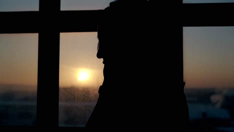 silhouette of woman at large window in dark flat close view