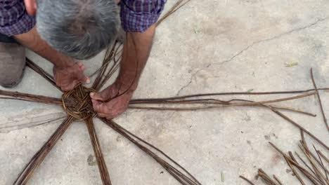 Un-Hombre-Teje-Mimbre-Usando-Material-Natural-Ramas-De-Madera-Eco-Planta-Artesanía-Arbustos-Follaje-Para-Hacer-Muebles-Cesta-Taller-Tradicional-Local-Arte-Persa-Bambú-Tienda-Sostenible-Granada-Rural