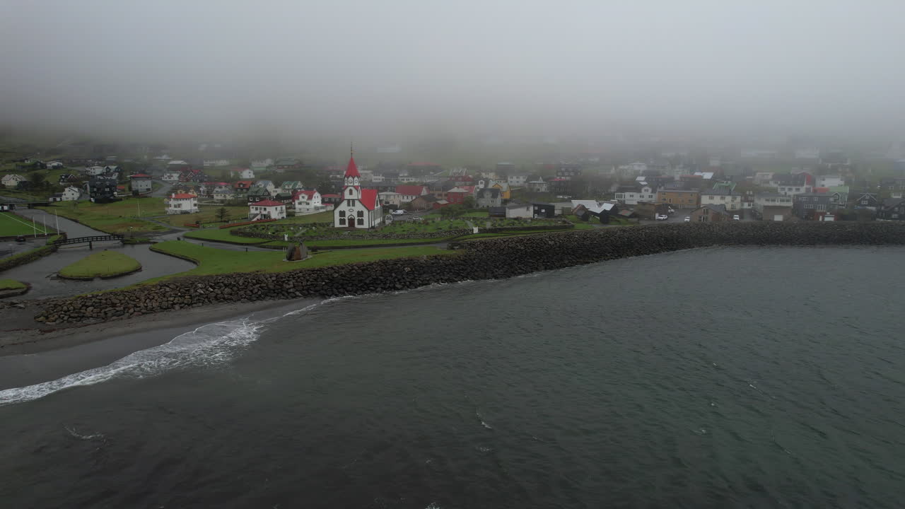 aldea de sandavagur, isla de vagar: vista aérea circular de la iglesia del pueblo en un día de niebla