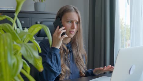 Young-entrepreneur-talking-on-phone-while-sitting-near-laptop