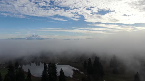 aerial flight by drone over a foggy landscape on a beautiful blue sky day with mottled clouds